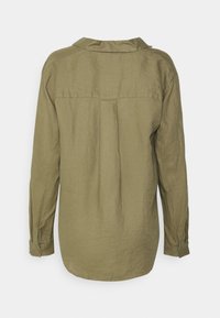 Camisa de linho de manga longa em verde oliva com colarinho, detalhe de plissado nas costas e punhos com botões. Textura suave, ajuste descontraído.