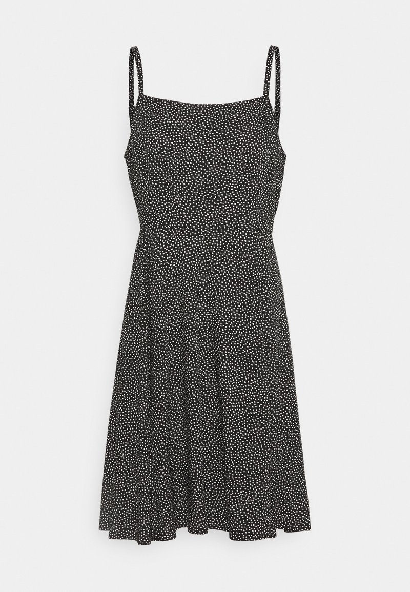 Robe noire à pois blancs, bretelles spaghetti, corsage ajusté et jupe évasée. Fabriquée en tissu léger.