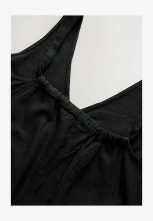 Top negro sin mangas con tirantes anchos, una cintura elástica fruncida y una tela suave y texturizada. Diseño minimalista con un escote en forma de V.