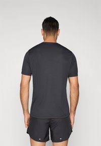 Camiseta deportiva de manga corta en gris oscuro, hecha de tela ligera, con cuello redondo y textura suave, combinada con pantalones cortos negros.