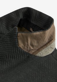 Czarny kaptur z tkaniny o teksturze w jodełkę, z brązowym kołnierzem wyściełanym siateczką oraz szarym akcentem.