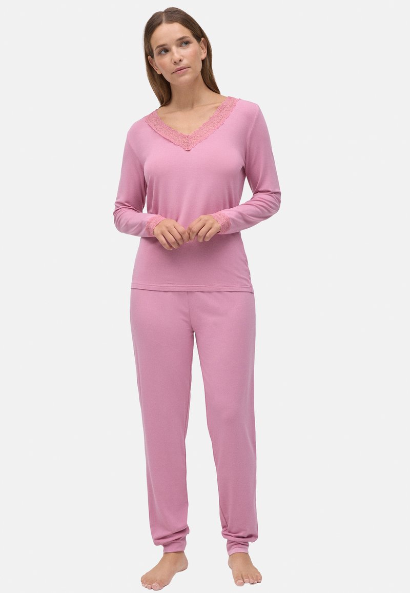 Conjunto de ropa de lounging rosa con mangas largas y pantalones. La parte superior cuenta con un escote en V con adornos de encaje; los pantalones son ajustados en los tobillos y están hechos de un tejido suave.