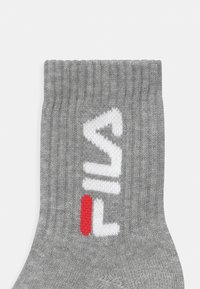 Calza in cotone grigia con texture a coste e logo bianco in evidenza con accento rosso. Altezza a metà polpaccio.