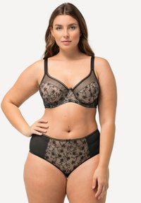 Ensemble de lingerie en dentelle noire avec broderies florales, tissu transparent et accents unis. Le soutien-gorge offre un soutien avec armatures et des bretelles ajustables.