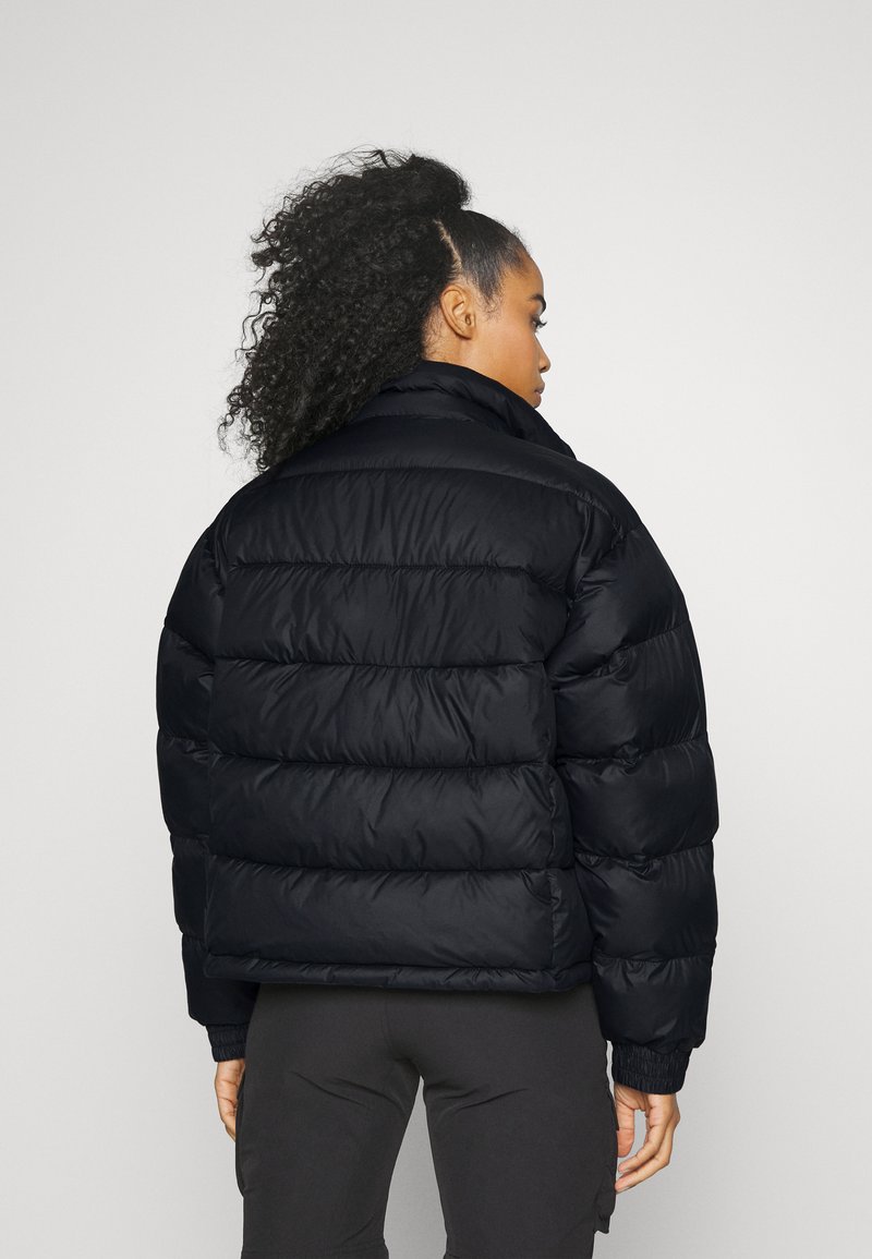 Chaqueta de plumas negra con un cuello alto, diseño acolchado y puños elásticos. El material parece suave con un acabado brillante.