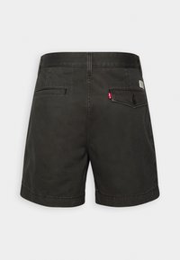 Shorts en coton noirs avec une coupe droite, poches arrière avec fermeture à bouton et une étiquette rouge sur la ceinture.