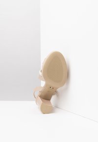 Sandalo nudo con tacco alto, dalla superficie liscia, con cinturini sottili e suola in gomma a motivo. Presenta un tacco a blocco ed etichetta "made in Italy".