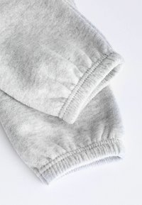 Grijze sweatshirtstof met geribbelde manchetten, zachte textuur en elastische randen. Het ontwerp heeft een casual, comfortabele stijl die geschikt is voor dagelijks gebruik.