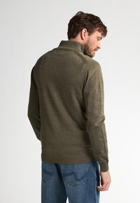 Olivgrüner Pullover mit hohem Kragen, gerippten Bündchen und Saum sowie einer glatten Textur, getragen mit blauen Jeans.