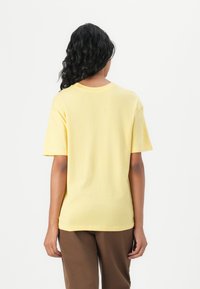 Gul bomull t-shirt med rund hals och korta ärmar, med en avslappnad passform. Slät textur, minimalistisk design och enfärgad.
