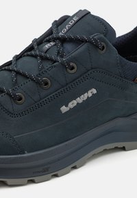 Donkerblauwe wandelschoen van nubuckleer met gaasaccenten, voorzien van een grijze rubberen zool, tonale veters en geborduurd logo.