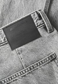 Hallide denim püksid musta nahklogoga vööl. Omadusteks on nähtavad õmblused, tekstureeritud kangas ja tagatasku.
