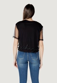 Top nero a maniche corte con maniche in rete, caratterizzato da un dettaglio testurizzato "scambio" all'orlo e abbinato a jeans blu.