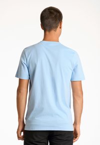 Vaaleansininen puuvillapaita, jossa on pyöreä kaula-aukko ja lyhyet hihat. Paidassa on sileä pinta ja takana ei ole kuvioita tai koristeita.