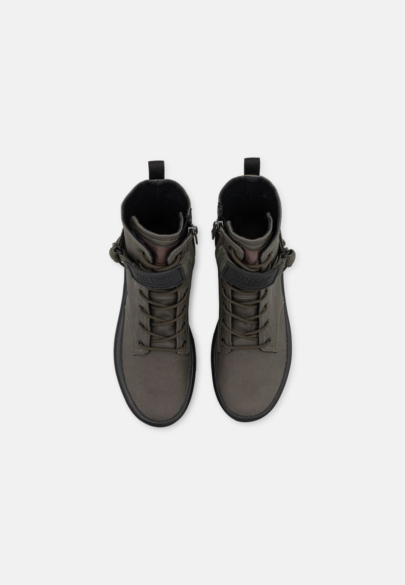 Un par de botas de caña alta de color gris oscuro con suelas negras, cordones y una correa de marca en la parte frontal, vistas desde arriba sobre un fondo blanco.