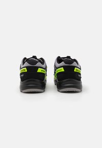 Black and grey athletic shoes with a mesh upper, featuring a bright green accent and branding, cushioned sole, and textured grip outsole.