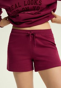 Burgundy shorts featuring a drawstring waist, made from soft cotton blend fabric, with a smooth texture and no visible patterns.