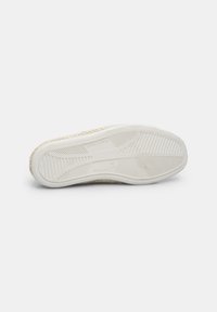 White sneaker sole with textured rubber grip and a woven straw accent along the edge, featuring a flared heel and a smooth surface.