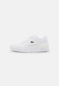 Zapatilla blanca de cuero con acentos perforados, punta redonda, suela plana de goma y logo de Lacoste bordado en verde en el lado exterior.