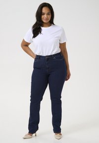 Dark blue high-waisted jeans with a slim fit and five-pocket design, paired with a plain white short-sleeve t-shirt.