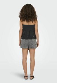 Top nero senza spalline con corpetto smock testurizzato e dettagli ricamati, abbinato a pantaloni corti in denim grigi, con cuciture visibili e design delle tasche.