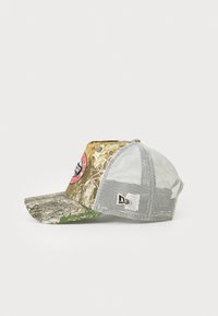 Casquette de baseball camouflage avec un dos en mesh, dotée d'un bord courbé, d'un patch logo sur le côté et de teintes terreuses de vert et de marron.