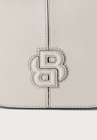 Lysegrå læderhåndtaske med en struktureret overflade, der har en markant præget hvid logo. Sømning med detaljer langs kanterne.