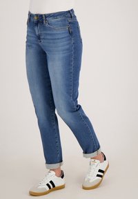 Lichtblauwe denim jeans met een rechte pijpdesign, opgerolde boorden en voorkwamen. Gecombineerd met witte sneakers met zwarte strepen.
