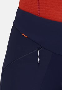Leggings de sport bleu marine avec une texture lisse, dotés d'un accent orange et d'une poche zippée sur le côté avec un cordon de serrage contrastant.