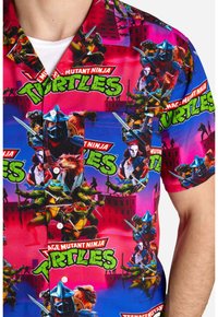 Camicia a maniche corte con una stampa multicolore di personaggi delle Tartarughe Ninja su uno sfondo rosa e blu.