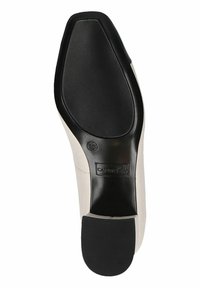 Sole dámských bot s hladkým krémovým povrchem, texturovanou černou gumovou podrážkou, zaobleným tvarem a embosovaným logem.