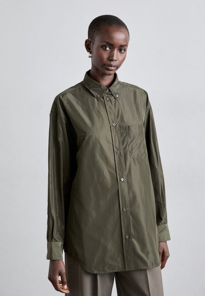 Chemise à manches longues, de couleur olive, avec des boutons, comprenant une poche poitrine, un ourlet arrondi et un léger éclat. Coupe ajustée avec des détails de boutons.