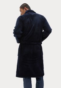 Granatowy, pluszowy szlafrok z kołnierzem typu szal, z paskiem w talii, długimi rękawami i miękką teksturą, widziany od tyłu.