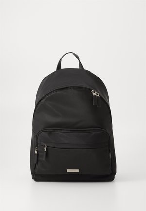 Sac à dos en nylon noir avec un sommet arrondi, deux compartiments zippés et une poignée en tissu. Quincaillerie argentée et plaque logo à l'avant.