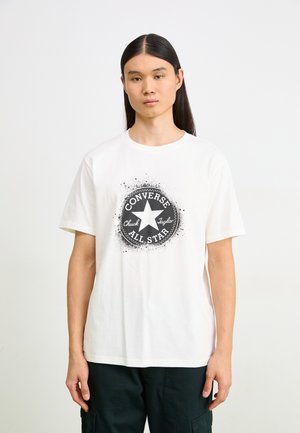 Weißes Baumwoll-T-Shirt mit einem schwarzen kreisförmigen Grafikdesign, das den Text "CONVERSE" und "ALL STAR" sowie ein zentrales Sternmotiv mit Spritzeffekt zeigt.