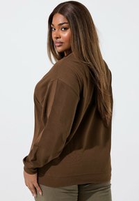 Brązowy, oversize sweatshirt z długimi rękawami, ściągaczami przy mankietach i u dołu. Miękka tekstura, luźny krój i minimalistyczny design.