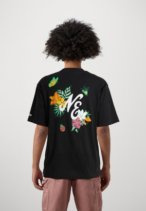 T-shirt nera con grafiche floreali colorate e farfalle sul retro, con un evidente design "N&" in bianco. Maniche corte, vestibilità morbida.