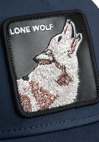 Casquette de baseball en tissu bleu marine ; elle présente un patch en cuir noir avec un loup brodé et le texte "LONE WOLF" en blanc.