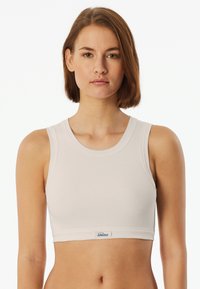 Světle šedý žebrovaný crop top s kulatým výstřihem a širokými ramínky. Obsahuje malou etiketu s nápisem "Schiesser" na lemu.