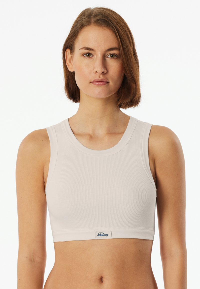 Světle šedý žebrovaný crop top s kulatým výstřihem a širokými ramínky. Obsahuje malou etiketu s nápisem "Schiesser" na lemu.