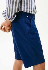 Marineblauwe shorts van lichtgewicht stof, met platte voorke pockets en een klein logoaccent op de achterzak met multikleurige details.