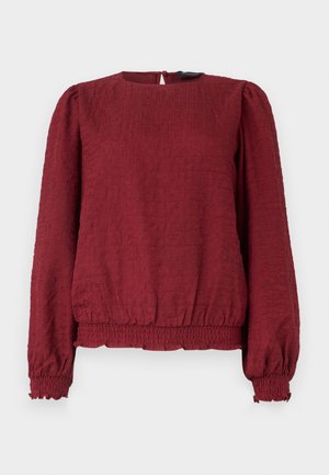 Blouse texturée bordeaux à manches longues avec encolure ronde, poignets et ourlet élastiqués, et fermeture par boutons au dos.