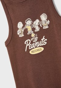 Hnědý tílko s potiskem kreslených postaviček hrajících na hudební nástroje a textem "Peanuts RECORDS" v bílé a žluté barvě.