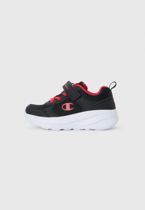 Chaussure de sport noire avec accents rouges, tige en maille, sangle Velcro réglable et semelle blanche rembourrée pour le confort et le soutien.