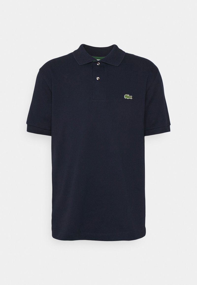 Polo en coton bleu marine avec un col court, deux boutons, et un logo Lacoste vert brodé sur le côté gauche de la poitrine.