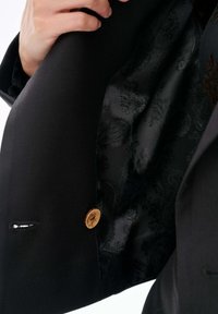 Czarna marynarka z złotym guzikiem, z misternym czarnym paisleyowym podszewką. Teksturowany zewnętrzny materiał o dopasowanym kroju.