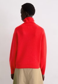 Roter, gerippter Rollkragenpullover mit langen Ärmeln und lockerem Sitz. Verfügt über eine dezente Textur und einen enganliegenden Bund am Saum.