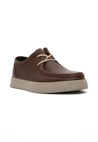 Scarpa in pelle marrone con suola in gomma leggera, forma tondeggiante e cuciture a contrasto. Caratterizzata da lacci beige e una texture liscia.