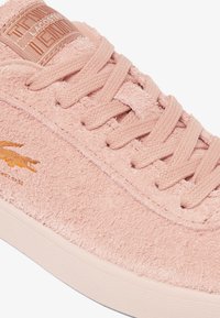 Sneaker in suede rosa con chiusura con lacci, parte superiore testurizzata e patch con logo impresso. Presenta una suola in gomma crema e un logo in coccodrillo arancione a contrasto.