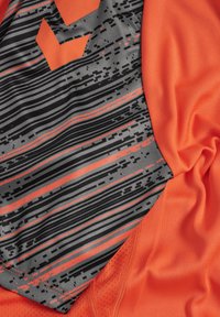 Camiseta deportiva naranja con un panel texturizado gris con rayas negras y acentos naranjas, que combina un diseño funcional con un color vibrante.